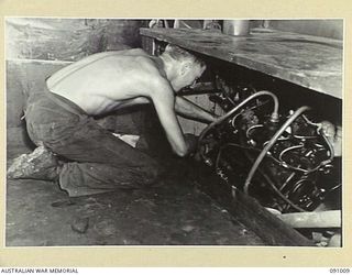 JACQUINOT BAY, NEW BRITAIN. 1945-04-17. SAPPER MILLER, MECHANIC AND ENGINEER, 41 LANDING CRAFT COMPANY, CHECKS OVER THE STARBOARD MOTOR BEFORE GOING OFF DUTY. IT IS ONE OF FOUR V8 FORD THORNYCROFT ..