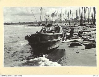 HANSA BAY, NEW GUINEA. 1944-06-17. WRECKED JAPANESE BARGES AMID A SCENE OF DEVASTATION ALONG THE WATERFRONT AFTER THE HEAVY ALLIED BOMBING OF THE AREA