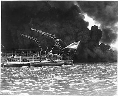 Naval photograph documenting the Japanese attack on Pearl Harbor, Hawaii which initiated US participation in World War II. Navy's caption: The colors still fly from the stern of the sunken battleship USS WEST VIRGINIA after the Japanese attack on Pearl Harbor, Dec. 7, 1941.