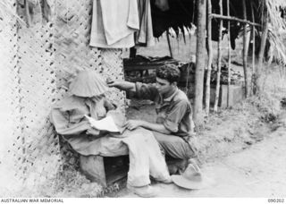 GOODENOUGH ISLAND, NEW GUINEA. 1942-10. DUMMIES REPRESENTING MEN LEISURELY READING WERE PART OF THE BLUFF AND DECEPTION PRACTICED BY A SMALL GROUP OF AUSTRALIANS WHO SEIZED THE ISLAND AND LED THE ..