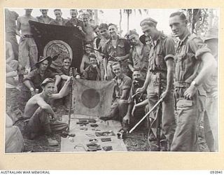 ULUPU, NEW GUINEA, 1945-07-09. 16 PLATOON, D COMPANY, 2/5 INFANTRY BATTALION WITH THE SPOILS OF THEIR SUCCESSFUL ATTACK ON THE MAIN JAPANESE STRONGHOLD IN THE VILLAGE. THEY INCLUDE 3 PISTOLS, 4 ..