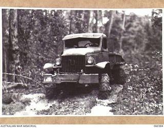 SOGERI, NEW GUINEA. 1943-11-20. A TIMBER HAULING TRUCK OF THE SCHOOL OF SIGNALS, NEW GUINEA FORCE MOVING ALONG A MUDDY JUNGLE TRACK TO PICK UP A LOAD OF LOGS FOR THE SAWMILL