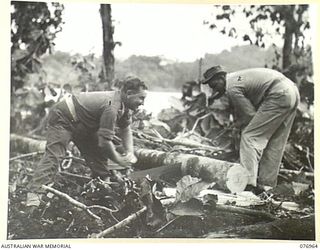 JACQUINOT BAY, NEW BRITAIN. 1944-11-14. NX58632 LIEUTENANT J.G. ROACHE, 2/14TH FIELD REGIMENT (1), LIAISON OFFICER TO THE 594TH UNITED STATES BARGE COMPANY, ASSISTING AMERICAN OFFICER LIEUTENANT ..