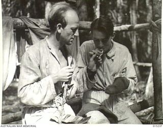 Wau-Mubo Area. At a Forward Dressing Station, N78920 Sergeant William Kilmister, of St Peters, NSW, and Private C Clarke, [possibly Clarence], are darning socks. (Negative by G Short)