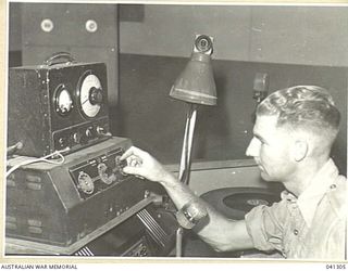 LAE, NEW GUINEA. 1945-09. ANNOUNCER OF LAE RADIO STATION, (9.AB) OPERATING AMPLIFIER FOR TURN TABLE AND MICROPHONE OF THE SET ORIGINALLY BUILT OF JUNK, MAINLY JAPANESE, BUT WITH SOME AUSTRALIAN AND ..