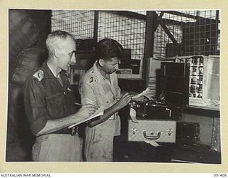 JACQUINOT BAY, NEW BRITAIN, 1945-04-28. CAPTAIN W.E. PARKER, AUSTRALIAN COMFORTS FUND COMMISSIONER (1) AND SERGEANT C.B. O'BRIEN (2), CHECKING A GRAMAPHONE AT THE AUSTRALIAN COMFORTS FUND STORE