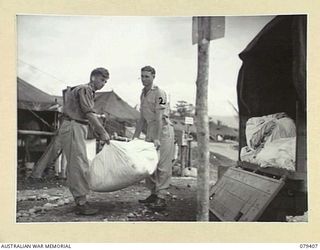 WUNUNG PLANTATION, JACQUENOT BAY, NEW BRITAIN. 2/3/1945. N87296 PRIVATE B.WORSLEY (1) and NX115404 CORPORAL F.L.FISHER (2)105th CASUALTY CLEARING STATION, loading soiled bed linen and clothes on to ..