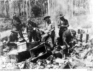 Madang, New Guinea. 1944-05. Australian troops inspect burning Japanese dumps at Madang