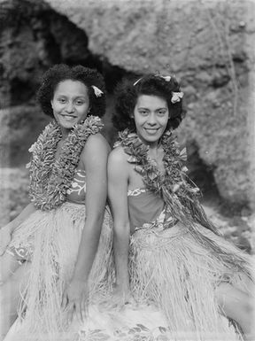 [Portrait of two young Polynesian girls sitting back-to-back]