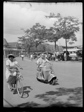 Street scene, Woman riding her bicycle and man riding his motor scooter, Papeete, Tahiti