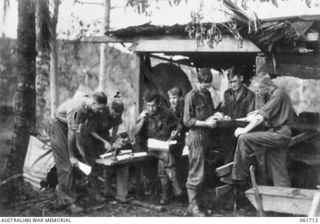 WAREO, NEW GUINEA. 1943-12-09. I SECTION OF THE 2/23RD AUSTRALIAN INFANTRY BATTALION AT WORK IN THEIR NEW QUARTERS. SHOWN ARE: VX38932 SERGEANT M. W. FERGUSON (1); VX40152 LIEUTENANT L. P. WENBORN ..