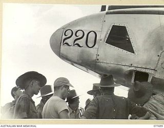 TOROKINA, BOUGAINVILLE ISLAND. 1944-12-23. WARRANT OFFICER J. REYNOLDS, NO.17 PHOTO SQUADRON, 13TH UNITED STATES AIR FORCE, EXPLAINING THE CAMERA EQUIPMENT INSTALLED IN ONE OF THE UNIT P38 LOCKHEED ..