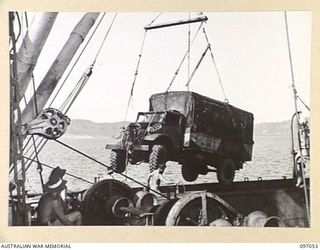 RABAUL, NEW BRITAIN. 1945-09-20. TROOPS OF 28 INFANTRY BATTALION SUPERVISING THE UNLOADING OF A VEHICLE IN A SLING OVER THE SIDE OF THE ANDREW BRISCOE TO BE TAKEN ASHORE BY ONE OF THE WAITING ..