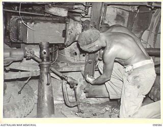 WAU, NEW GUINEA. 1945-10-17. PRIVATE J.B. FREEMAN, MECHANIC, 5 INDEPENDENT FARM PLATOON, REPAIRING A JEEP