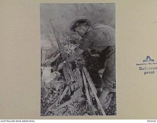 WIRUI MISSION, WEWAK AREA, NEW GUINEA, 1945-05-15. PRIVATE C.F. SADLER, 2/4 INFANTRY BATTALION EXAMINING A BROWNING MACHINE-GUN. THE MISSION AND AREA WAS VERY HEAVILY DEFENDED WITH A VARIETY OF ..