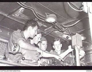 TOROKINA, BOUGAINVILLE, 1945-10-27. GUNNER R. DAWSON (1), PRIVATE F. BRUHN (2), AND GUNNER J. FITZHENRY (3), LEARNING THE CORRECT METHOD OF SETTING A FOUR JAW CHUCK ON A LATHE, UNDER THE CAPABLE ..