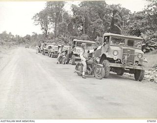 LAE, NEW GUINEA. 1944-09-21. MEMBERS OF THE NEW GUINEA FORCE PROVOST COMPANY EXAMINING THE ORDERS OF AN AUSTRALIAN ARMY CONVOY. IDENTIFIED PERSONNEL ARE:- SERGEANT A.J. DENSMORE (1); CRAFTSMAN J.E. ..