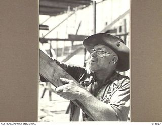 1943-05-10. NEW GUINEA. THIS PHOTO IS ONE OF THE FIRST TO ARRIVE IN AUSTRALIA SHOWING THE CORPS AT WORK IN NEW GUINEA. JIM ALLERSLADE OF DARWIN HANDS A PLANK TO ANOTHER WORKMAN. (NEGATIVE BY F. ..