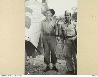 PORT MORESBY, PAPUA, 1944-02-25. AN AUSTRALIAN SOLDIER AND AN AMERICAN SERVICEMAN ARRIVING WITH PORTABLE SEATS AT A FIELD CINEMA. THE PICTURES ARE SHOWN AT HEADQUARTERS, NEW GUINEA FORCE BY THE ..