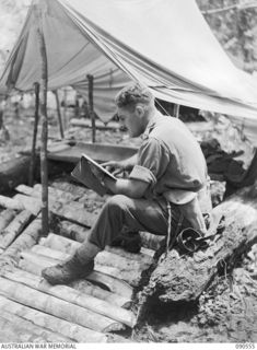 WONGINARA MISSION, NEW GUINEA. 1945-04-06. LIEUTENANT COLONEL I. HUTCHISON, COMMANDING OFFICER, 2/3 INFANTRY BATTALION, EXAMINING A MAP OUTSIDE HIS "DOOVER"