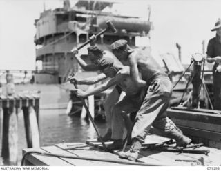 PORT MORESBY, PAPUA, 1944-03-21. MEMBERS OF THE 2/16TH FIELD COMPANY, ROYAL AUSTRALIAN ENGINEERS, FIXING THE DECKING OF A NEW NAVAL OIL WHARF INTO POSITION WITH CROWBARS. IDENTIFIED PERSONNEL ARE: ..