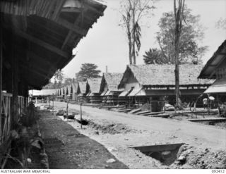 LAE, NEW GUINEA, 1945-05. GENERAL VIEW OF THE AWAS BARRACKS. IN THE FOREGROUND IS A GLIMPSE OF THE BIG RECREATION HUT
