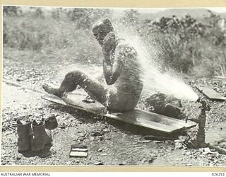 PORT MORESBY, PAPUA. 1942-08. ONE WAY TO KEEP COOL IN NEW GUINEA. THIS AUSTRALIAN SOLDIER SEEMS TO BE ENJOYING HIS BATH AT A ROAD HYDRANT IN PORT MORESBY