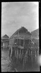 Children sitting on porch of stilted house over water at Gaile, a Motu village