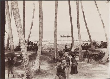 Villagers walking amongst trees near shore, canoe in background, Halavo, Solomon Islands, 1906 / J.W. Beattie