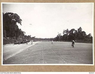 DREGER HARBOUR, NEW GUINEA. 1943-12-06. VIEW FROM THE CENTRE OF THE NEW LANDING STRIP BUILT BY ENGINEERS OF THE 870TH UNITED STATES AVIATION ENGINEER BATTALION, SHOWING A TIGER CUB AIRCRAFT PARKED ..