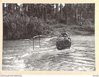 BOUGAINVILLE. 1945-06-09. GENERAL SIR THOMAS A. BLAMEY, COMMANDER-IN-CHIEF, ALLIED LAND FORCES, SOUTH WEST PACIFIC AREA (1), CROSSING THE HONGORAI RIVER IN A JEEP DURING HIS VISIT TO 15 INFANTRY ..