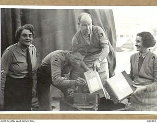 MEMBERS OF THE 3RD BASE ORDNANCE DEPOT AT WILSON STREET, TROPIC PROOFING PACKAGES OF SPARE PARTS BY DIPPING THEM IN HOT WAX BEFORE DESPATCHING THEM TO NEW GUINEA. NOTE THE LABELS DENOTING CONTENTS ..