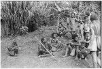 Men sitting around in front of men's house in background