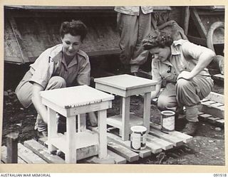 LAE, NEW GUINEA. 1945-05-08. PRIVATE R. BENSLEY (1) AND PRIVATE G.P. BIRRELL (2), PAINTING BEDSIDE STOOLS AFTER SETTLING IN AT THE NEWLY CONSTRUCTED AWAS BARRACKS IN BUTIBUM ROAD. THEY ARE MEMBERS ..