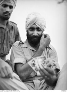 PORT MORESBY, NEW GUINEA. 1944-05-31. LANCE-CORPORAL SOHAN SINGH (1), 5/11TH SIKH REGIMENT, CONTEMPLATES THE RIGHT CARD DURING A GAME OF BRIDGE AT THE NEW GUINEA DETAILS DEPOT. MEMBERS OF THE ..
