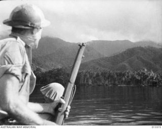 1942-10-01. NEW GUINEA. MILNE BAY. THIS IS TYPICAL OF THE COUNTRY AROUND WHERE AUSTRALIAN MILITIA FORCES REPULSED JAPANESE ATTEMPS TO LAND. SURVEYING THE SCENE IS CORPORAL HAROLD JACOBS, 55TH ..