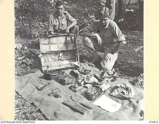 LAE, NEW GUINEA. 1944-07-01. PRIVATE A.R. BARRING (1) AND VX104088 LIEUTENANT A.W. MCMICHAEL (2) OF THE INTELLIGENCE SECTION, HEADQUARTERS, NEW GUINEA FORCE, EXAMINING JAPANESE EQUIPMENT WHICH WAS ..