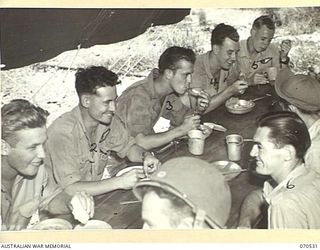 JACKSON'S DROME, PORT MORESBY, PAPUA, 1944-02. AUSTRALIAN AND AMERICAN AIRMEN DISCUSSING EXPERIENCES OVER THEIR MID DAY MEAL AT JACKSON'S DROME. THESE MEMBERS OF THE ROYAL AUSTRALIAN AIR FORCE ARE ..