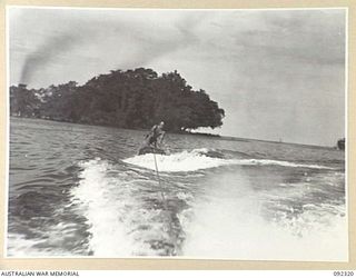 JACQUINOT BAY, NEW BRITAIN, 1945-05-20. ABLE SEAMAN P. MARSHALL, ROYAL AUSTRALIAN NAVY, THRILLS THE CROWD WITH AN AQUAPLANING DISPLAY AT THE GRAND CARNIVAL OF THE JACQUINOT BAY YACHT CLUB AND ..