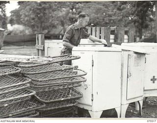 MADANG, NEW GUINEA. 1944-08-25. SX11013 PRIVATE V.D. MORGAN, STOREMAN, CHECKING THROUGH A CONSIGNMENT OF REFRIGERATORS AND MATRESSES AT THE 2/11TH GENERAL HOSPITAL