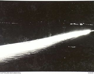 PORT MORESBY, NEW GUINEA. 1943-06-26. NIGHT PHOTOGRAPH OF CONVOY OF HEAVY TRUCKS MOVING ALONG PORT MORESBY ROAD