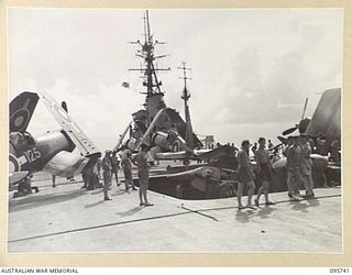 AT SEA OFF RABAUL, NEW BRITAIN. 1945-09-06. CORSAIR AIRCRAFT COMING UP IN THE LIFT TO THE FLIGHT DECK OF AIRCRAFT CARRIER HMS GLORY. THE CORSAIRS PROVIDED AIR COVER DURING THE SIGNING OF THE ..