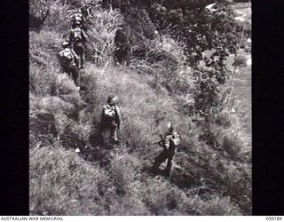 LALOKI VALLEY, NEW GUINEA. 1943-11-05. WITH THE RIVER ON THE RIGHT, A PATROL FROM THE NEW GUINEA FORCE TRAINING SCHOOL (JUNGLE WING) IS PASSING OVER A STEEP SLOPE ON ITS BANK ON AN EXERCISE NEAR ..