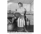 Mr. Brock holding a turtle captured at Namu Island, 1947