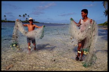 Two young men with fishing nets in lagoon, Rakahanga, Cook Islands