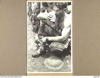 SHAGGY RIDGE, NEW GUINEA. 1944-01-22. A WOUNDED SOLDIER, QX16556 PRIVATE E. KNIGHT OF THE 2/9TH INFANTRY BATTALION ENJOYING A CUP OF COFFEE AT A FORWARD REGIMENTAL AID POST DURING THE BATTLE FOR ..