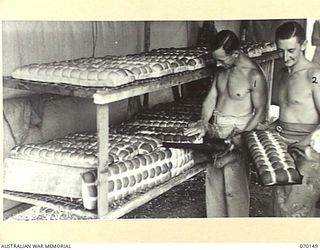 DUMPU, NEW GUINEA. 1944-02-05. VX139868 CORPORAL R.H. PAGE (1) OF THE 24TH INFANTRY BATTALION AND VX144966 PRIVATE J. STEWART (2) OF THE 57/60TH INFANTRY BATTALION, PICTURED IN THE BREAD ROOM OF ..