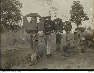 KIRIWINA, TROBRIAND ISLANDS, PAPUA. C. 1943-11. ARMOURERS OF NO. 8 SQUADRON RAAF WALKING ALONG A TRACK CARRYING TAILPIECES FOR 2000LB BOMBS