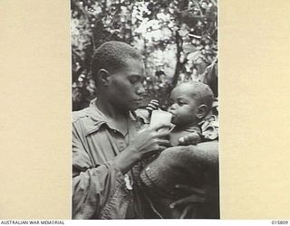 1943-09-25. NEW GUINEA. FALL OF LAE. LEAH, FIFTEEN YEARS OLD NATIVE GIRL WITH A SIX MONTHS OLD BABY. LEAH ESCAPED FROM THE JAPANESE LINES JUST BEFORE THE FALL OF LAE