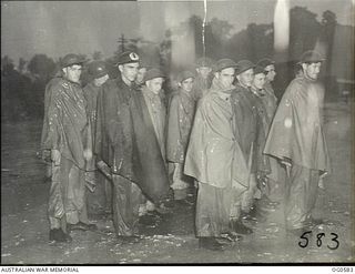KIRIWINA, TROBRIAND ISLANDS, PAPUA. C. 1944-02. HAIL, RAIN OR SHINE, RAAF GUARDS IN NEW GUINEA ARE ON THE JOB DAY AND NIGHT. INFORMAL GROUP PORTRAIT OF GUARDS GOING ON DUTY DURING THE "WETTER" ..